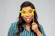 party props, photo booth and people concept - happy asian young woman with big glasses in shape of stars sticking out her tongue over grey background