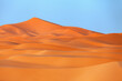 Sand dunes in the desert with blue sky background.