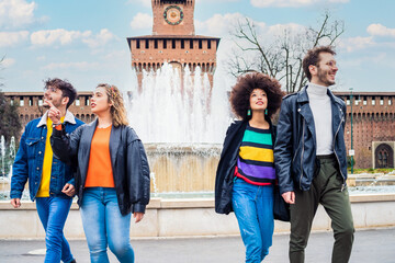 Group of friends tourist walking together outdoors in the city downtown