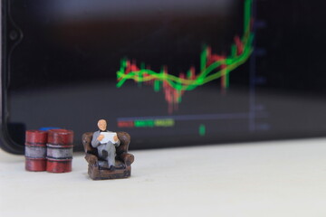 Wall Mural - Simple Conceptual Photo, illustration for Senior Investor Mini Figure Toy businessman Seriously watching Running Stock Exchange Sitting at sofa beside Oil Barrel
