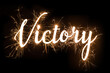 Cursive word of 'Victory' in dazzling sparkler effect on dark background