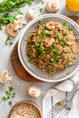 Wall Mural - Quinoa stewed with mushrooms, onions, garlic, and parsley in a plate on a gray concrete background top view. Delicious and healthy vegetarian food. Quinoa with champignons.