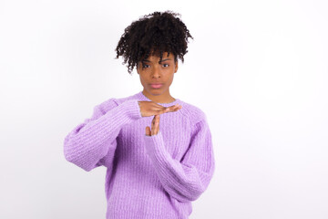 Wall Mural - oung beautiful African American woman wearing purple knitted sweater against white wall being upset showing a timeout gesture, needs stop, asks time for rest after hard work, demonstrates break hand