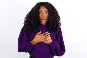 Wall Mural - Scared Young beautiful African American woman looks with frightened expression, keeps hands on chest, being puzzled to notice something strange, People, hush reaction and emotions.