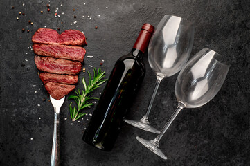 Wall Mural -  Different degrees of roasting heart-shaped beef steak with spices on a meat fork and a bottle of red wine on a stone background with copy space for your text