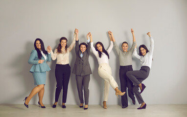 Wall Mural - Excited young businesswomen celebrating their success, holding hands and smiling