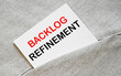 BACKLOG REFINEMENT text on the white sticker in the shirt pocket.
