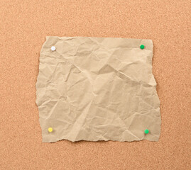 Wall Mural - brown piece of torn paper pinned with iron buttons on a brown cork board