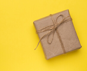 square box with a gift wrapped in brown paper and tied with a brown ro