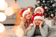 © Andrii  - Family in santa claus hats lie on the floor of decorated room