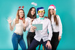 © Elizaveta - New Year theme Christmas winter office company employees. Group 4 young Caucasian people business smile holiday funny hats accessories glasses take photo yourself selfie tablet blued background
