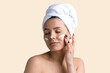 © Mountains Hunter - Beauty portrait of woman in white towel on head applies cream to the face. Skincare cleansing eco organic cosmetic spa relax concept.