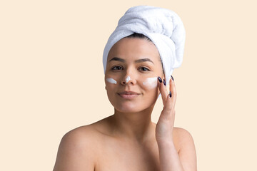 Beauty portrait of woman in white towel on head applies cream to the face. Skincare cleansing eco organic cosmetic spa relax concept.