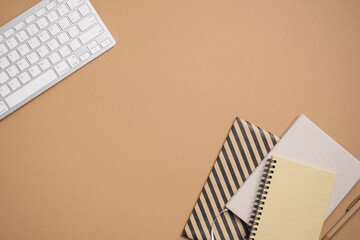 Poster - Home office desk top view with keyboard, paper notebooks, notepad, pen on beige background. Flat lay, view from above. Elegant feminine workspace with stylish stationery. Business concept.