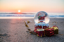 Christmas Snow Ball Globe On The Beach, By The Sea As A Symbol Of  Christmas At Resort
