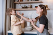 Family fun in the kitchen. Mother and son baking carrot cake together. Scandinavian kitchen interior. Mom holds a beater and plays with her son, rubs his nose with whipped cream