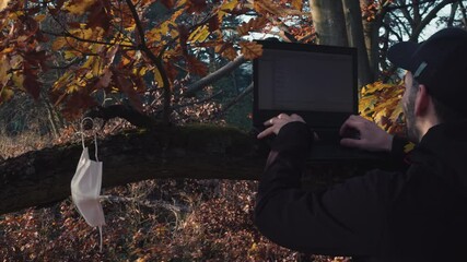 Male using laptop in forest during covid pandemic, workaholic concept