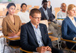 © JackF - Young confident man sitting in conference hall and listening to speaker on business training