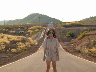 Wall Mural - A woman wearing a hat and glasses is standing in the middle of the road.