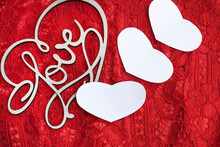 On A Red Openwork Background Lies A Wooden Heart With The Inscription Love And Next To It Three White Hearts. Festive Background With Space For Text.