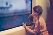 © natalialeb - Caucasian little girl child with pigtails listens to music in headphones and looks out the window in a train with a toy bear, travel concept, child travels alone