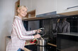 © zinkevych - Woman standing near the stove in the kitchen and smiling