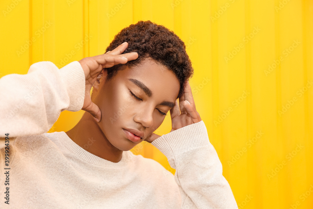 Stylish young African-American man near color wall