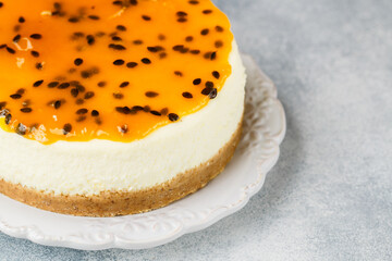 Wall Mural - Passion fruit cheesecake on a white plate on a gray concrete background. Delicious homemade cake. Selective focus, copy space