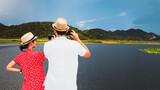 Fototapeta Dziecięca - Man and woman taking pictures of landscapes on smartphones - married couple on vacation - social networks post photo