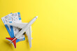 © New Africa - Toy airplane and tickets on yellow background, flat lay. Space for text