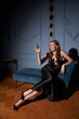 © Dmitry Tsvetkov - Elegant lady in black long evening dress sitting at sofa in black silk dress and holding glass of sparkling wine. Celebrating concept.