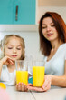 © DSMT - Mother with little girl drinking orange juice while they have breakfast together