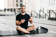 © Ivan - Man resting after outdoors excercising with smartphone in hand and thumbing up. Sports water bottle on black yoga mat. Sporty man after practicing yoga, relaxing on mat, texting on phone.
