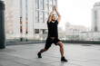 © Ivan - Athletic man practice Low Lunge pose with raised arms. Young man in black sports t-shirt and leggins stretching in yoga pose. Urban sport concept. Morning warm up.