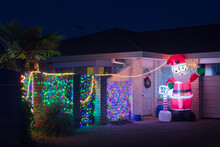 Christmas Decorations In A Suburban Garden At Night. Colorful Lights And An Inflatable Santa