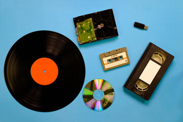 Wall Mural - A collection of old and modern storage devices technology, Gramophone record videocassette audiocassette tape compact disk hard disk and flash drive on blue background