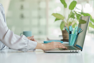 Leinwandbilder - Close up view of female working with laptop on a white table in the office room.	