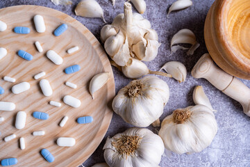 Closeup of pills on a wooden plate and garlic on the side