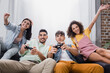 © LIGHTFIELD STUDIOS - Cheerful hispanic friends playing video game at home