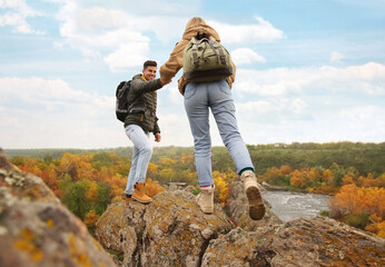 Sticker - Couple of hikers with backpacks climbing up mountains