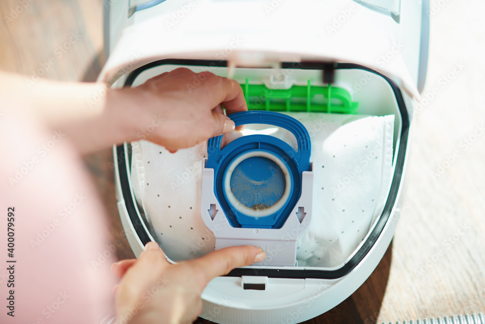 woman at home in sunny day changing vacuum cleaner bag