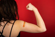 © Mat Hayward - Female arm flexing bicep and making a fist wearing a bandage after receiving a Covid-19 Coronavirus vaccine injection