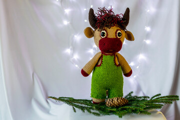 Wall Mural - Handmade doll Amigurumi bull. Spruce branch with cones. White background.