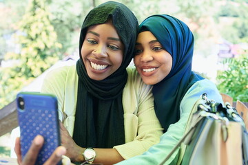 Wall Mural - african female friends using smart phone together