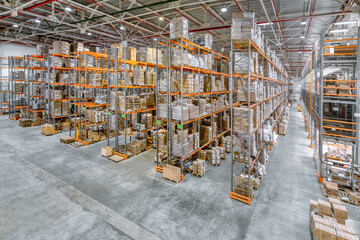 Large industrial warehouse. Tall racks are completely filled with boxes and containers.