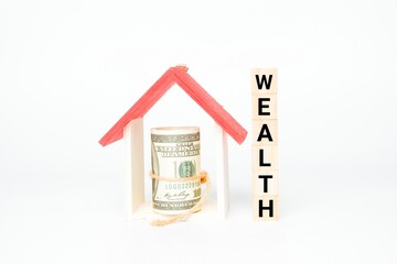 A picture of house miniature and fake money with wooden block written wealth. Wealth management concept.