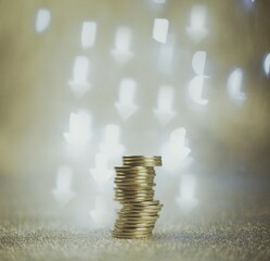 coins stacked on a dark background with bokeh of hearts and arrows