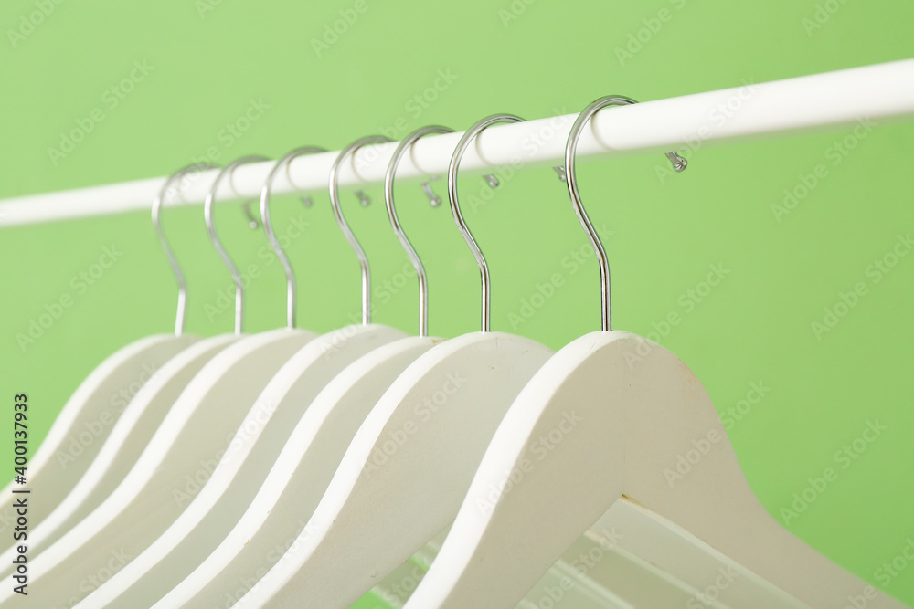 Rack with clothes hangers on color background, closeup