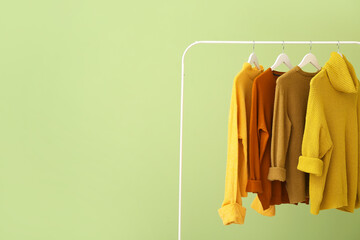 Rack with clothes on color background