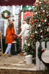 Poster - Happy young couple near house decorated for Christmas